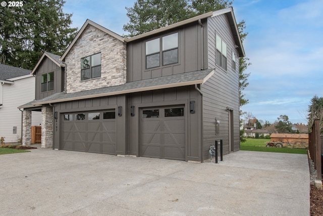 exterior space with an attached garage, stone siding, driveway, roof with shingles, and board and batten siding