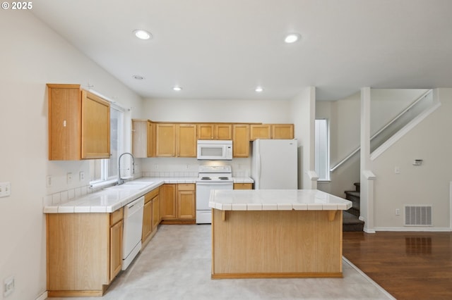 kitchen with white appliances, tile countertops, a center island, and sink