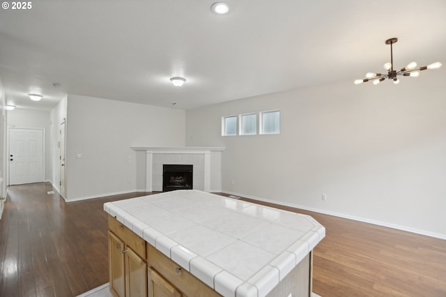 kitchen featuring a fireplace, tile countertops, hanging light fixtures, and a kitchen island