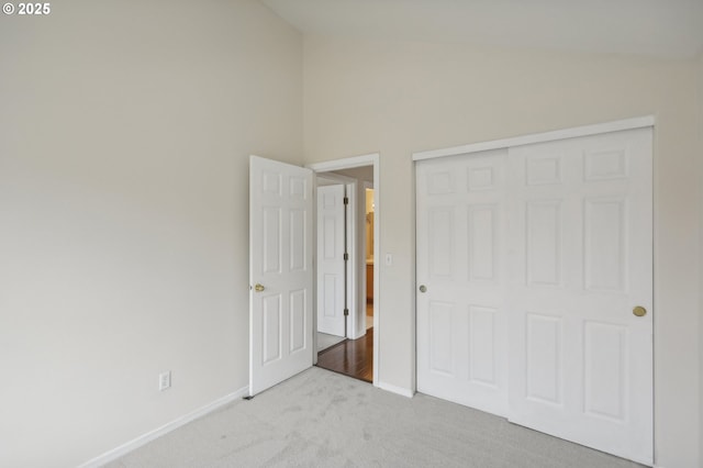 unfurnished bedroom with lofted ceiling, light colored carpet, and a closet