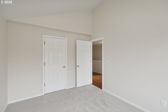 unfurnished bedroom with high vaulted ceiling and light carpet