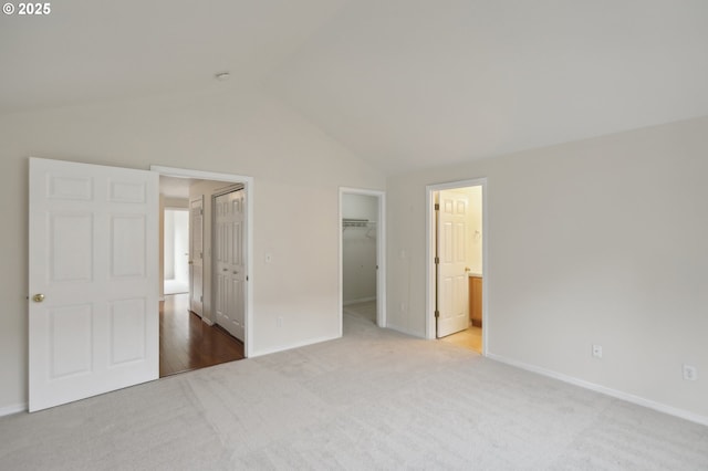 unfurnished bedroom with carpet floors, connected bathroom, a spacious closet, and vaulted ceiling