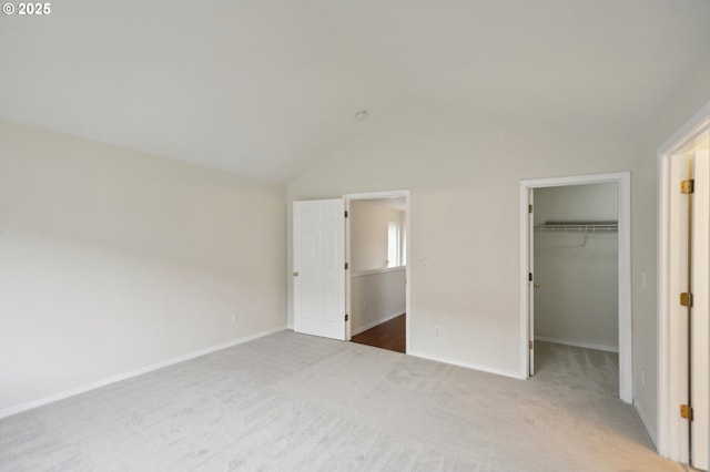 unfurnished bedroom featuring a spacious closet, vaulted ceiling, a closet, and carpet