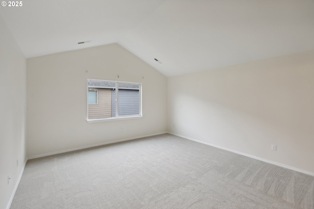 carpeted spare room featuring vaulted ceiling