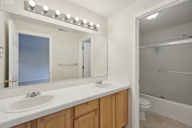 full bathroom featuring vanity, shower / bath combination with glass door, and toilet