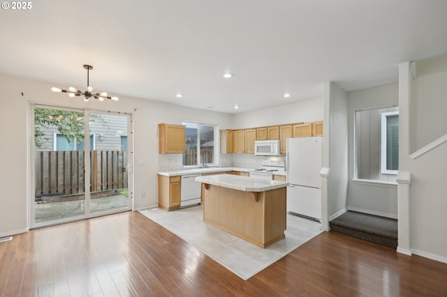 kitchen featuring pendant lighting, white appliances, a notable chandelier, light hardwood / wood-style floors, and a kitchen island