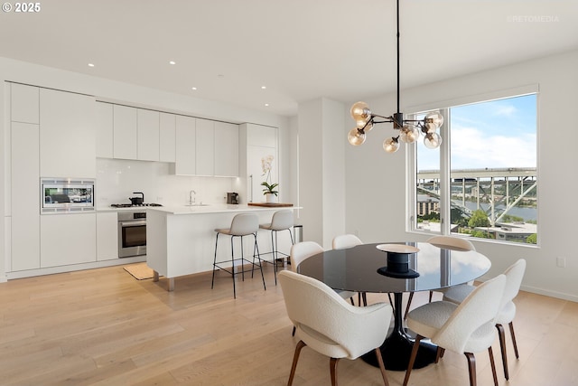 dining area featuring a chandelier, light wood-style flooring, and recessed lighting