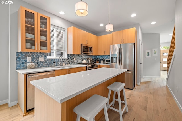 1011 NE 73rd Ave, Portland, OR 97213 - kitchen featuring appliances with stainless steel finishes, tasteful backsplash, a kitchen breakfast bar, light wood-style floors, and a center island