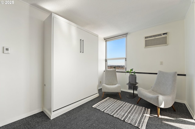 living area featuring an AC wall unit, dark carpet, and baseboards