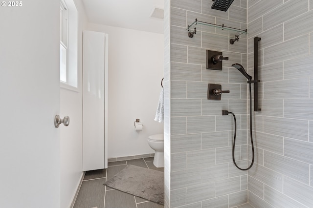 65 SW Frenwood Way, Beaverton, OR 97005 - bathroom featuring toilet, tiled shower, baseboards, and tile patterned flooring