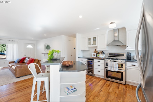 65 SW Frenwood Way, Beaverton, OR 97005 - kitchen with appliances with stainless steel finishes, wall chimney range hood, dark countertops, beverage cooler, and recessed lighting