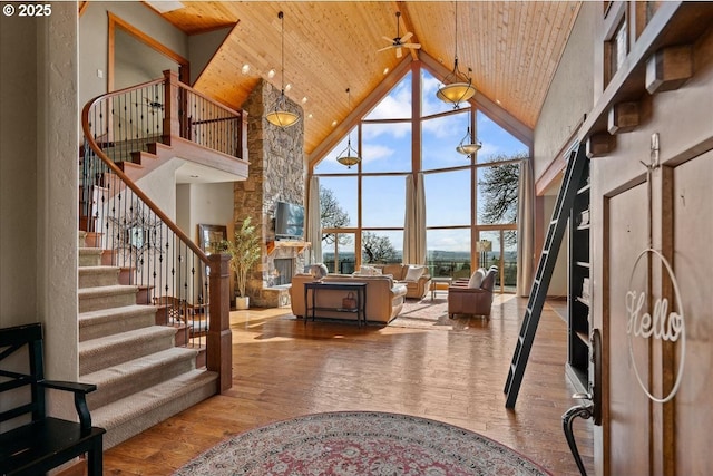 entrance foyer featuring wooden ceiling, stairway, hardwood / wood-style floors, a fireplace, and high vaulted ceiling