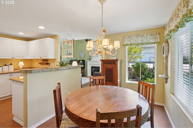 16199 SW Audubon St Unit 101, Beaverton, OR 97003 - dining space with light wood finished floors, a chandelier, recessed lighting, baseboards, and a fireplace