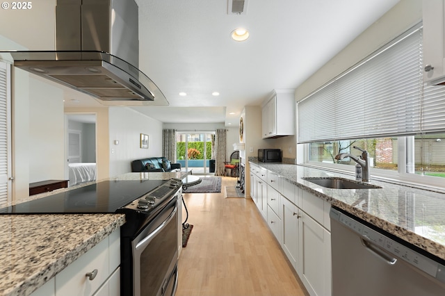kitchen with wall chimney range hood, open floor plan, visible vents, stainless steel appliances, and a sink