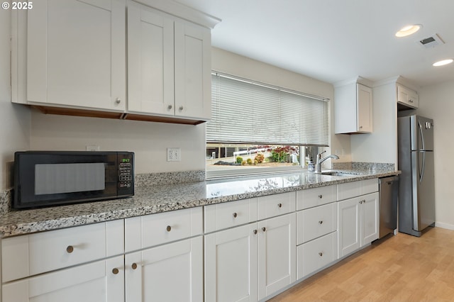 kitchen featuring a sink, light wood finished floors, white cabinetry, recessed lighting, and stainless steel appliances