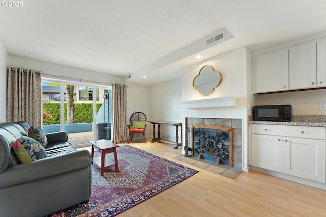 living area featuring visible vents, recessed lighting, light wood-style floors, and a fireplace