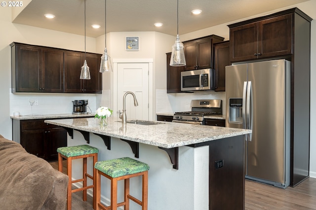 2314 SW 43rd St, Gresham, OR 97080 - kitchen with stainless steel appliances, dark brown cabinetry, decorative backsplash, wood finished floors, and a kitchen breakfast bar
