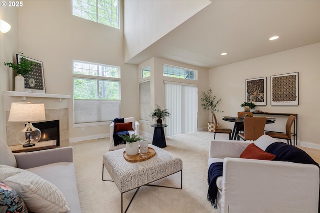 living area featuring carpet floors, baseboards, recessed lighting, a tiled fireplace, and a towering ceiling
