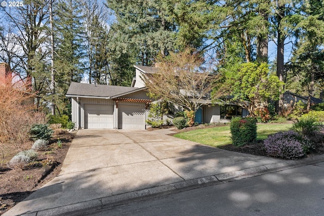 view of front of home featuring concrete driveway, an attached garage, a front lawn, and a shingled roof