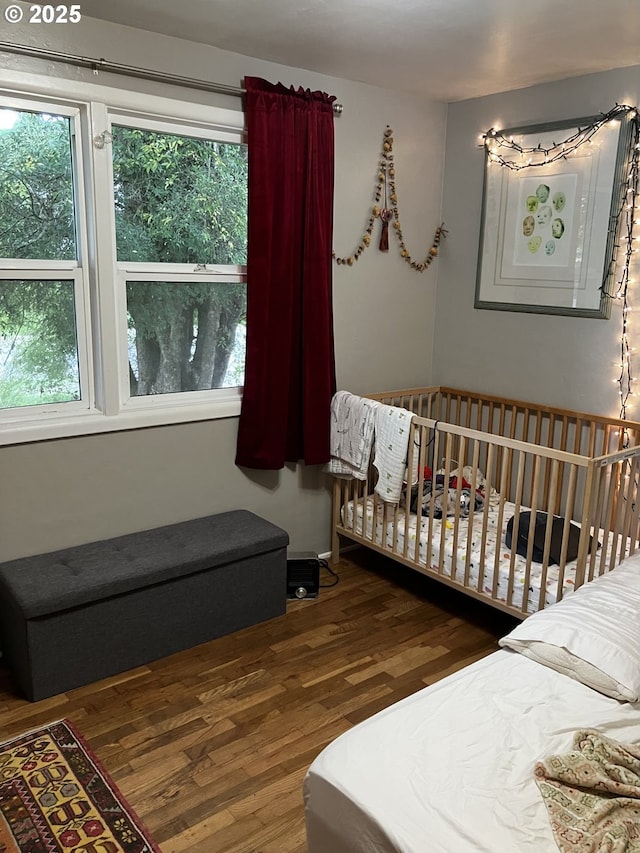 bedroom featuring a crib and wood finished floors