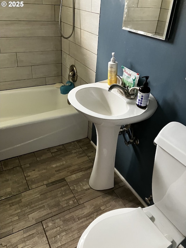 full bathroom featuring washtub / shower combination, toilet, and wood finished floors