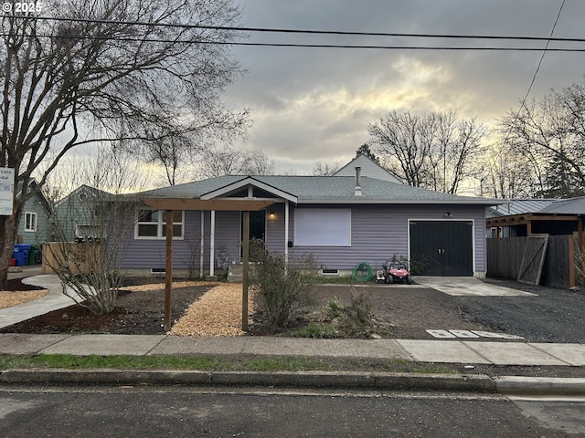 view of front of property with driveway, a shingled roof, a garage, and fence