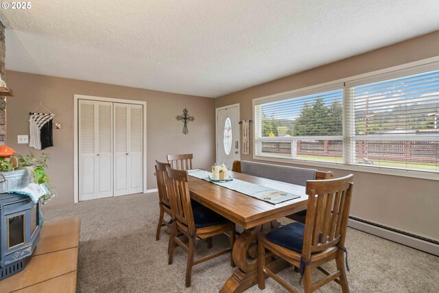 772 Elochoman Valley Rd, Cathlamet, WA 98612 - dining area featuring a textured ceiling, carpet flooring, a wood stove, and a baseboard heating unit