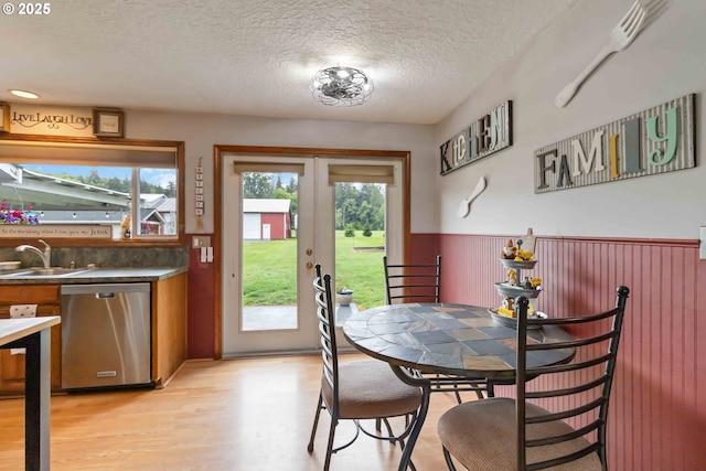 772 Elochoman Valley Rd, Cathlamet, WA 98612 - dining area featuring a textured ceiling, french doors, wainscoting, and light wood-type flooring