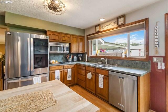 772 Elochoman Valley Rd, Cathlamet, WA 98612 - kitchen with stainless steel appliances, a sink, brown cabinets, light wood-style flooring, and tasteful backsplash
