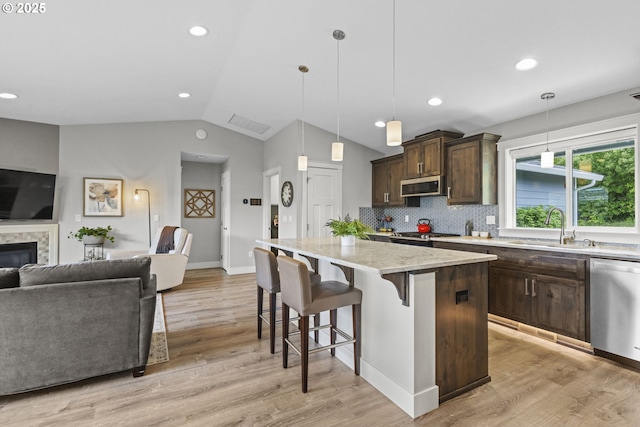 4635 Chaucer Ct, Depoe Bay, OR 97341 - kitchen featuring open floor plan, appliances with stainless steel finishes, lofted ceiling, dark brown cabinets, and a breakfast bar