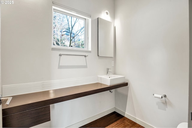 bathroom with wood finished floors, baseboards, and a sink