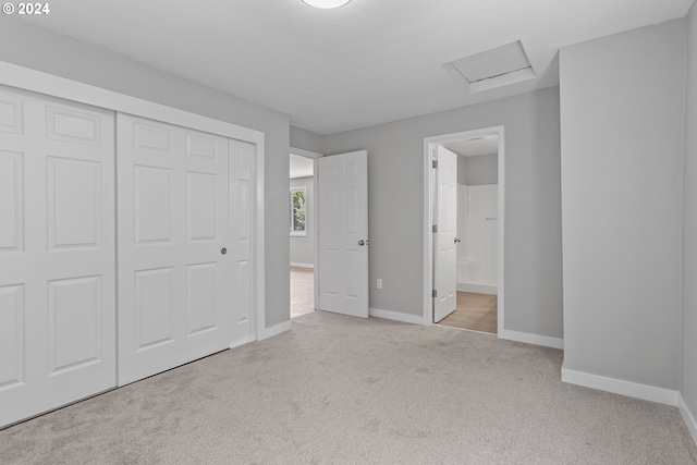 unfurnished bedroom featuring carpet floors, a closet, baseboards, attic access, and connected bathroom