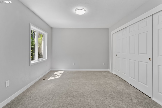 unfurnished bedroom featuring carpet floors, baseboards, a closet, and visible vents