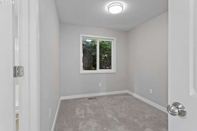 spare room featuring carpet flooring, a textured ceiling, visible vents, and baseboards