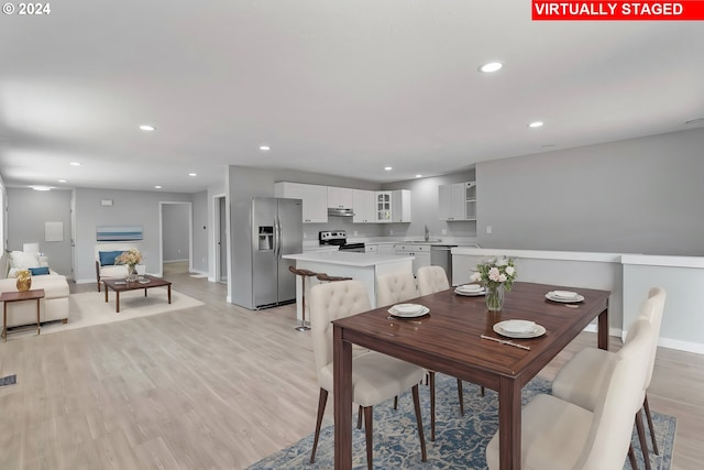 dining space featuring baseboards, light wood finished floors, and recessed lighting