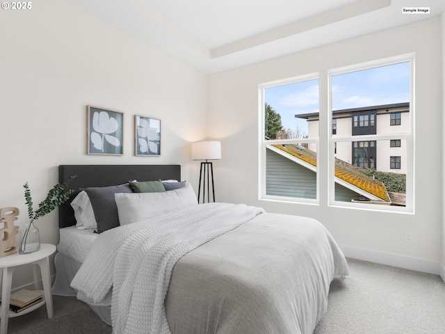 bedroom with a tray ceiling, baseboards, carpet floors, and visible vents