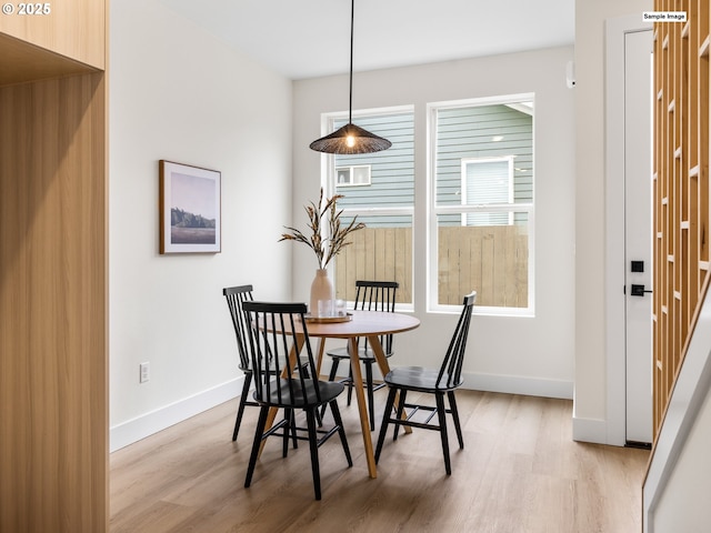 dining area with light wood-type flooring and baseboards