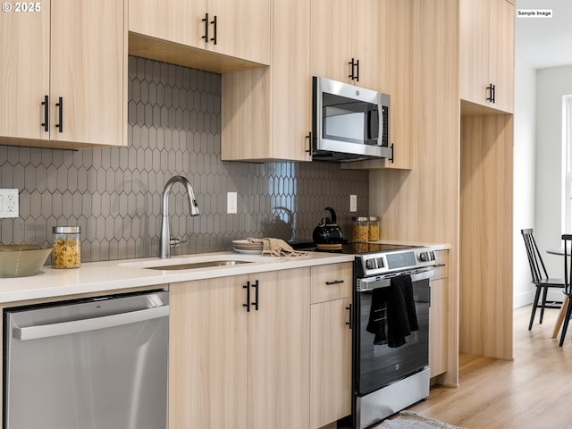 kitchen with light brown cabinets, appliances with stainless steel finishes, modern cabinets, and a sink