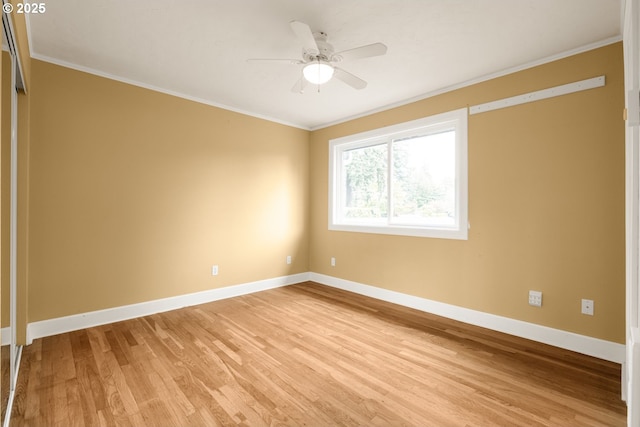 empty room with ornamental molding, light wood-type flooring, baseboards, and a ceiling fan