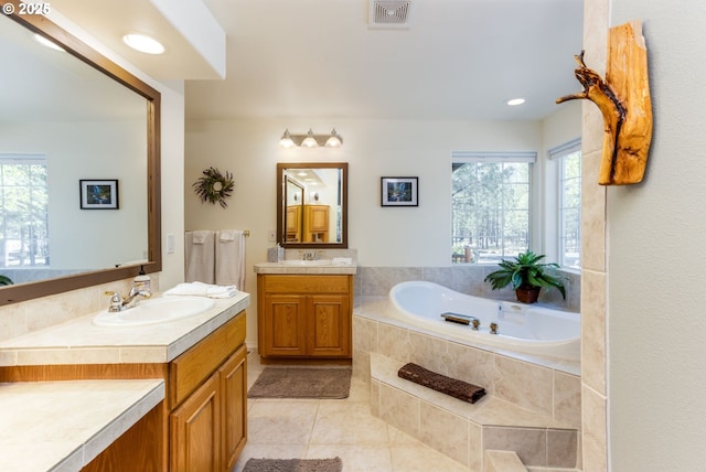 bathroom with tiled bath, tile patterned flooring, and vanity