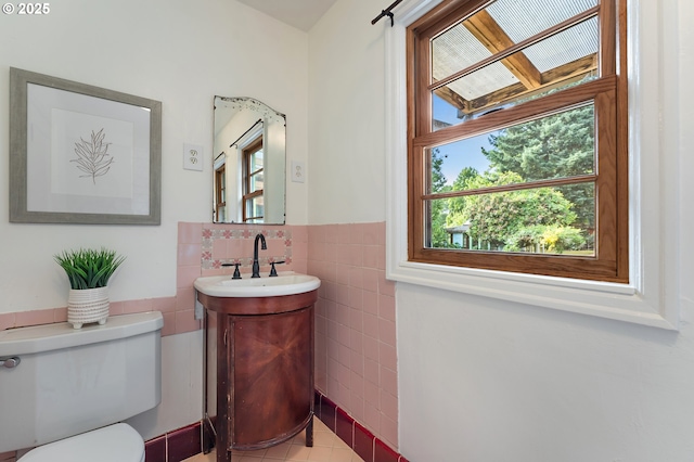 4650 NE Simpson St, Portland, OR 97218 - bathroom with tile walls, vanity, toilet, wainscoting, and tile patterned flooring