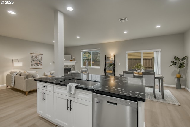 kitchen with visible vents, stainless steel dishwasher, open floor plan, white cabinetry, and a sink