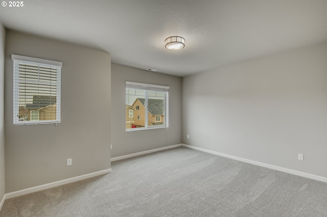 carpeted empty room with baseboards and a textured ceiling