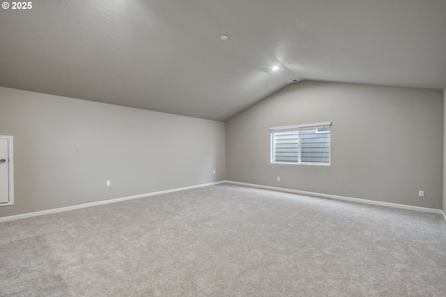 additional living space with lofted ceiling, light colored carpet, and baseboards