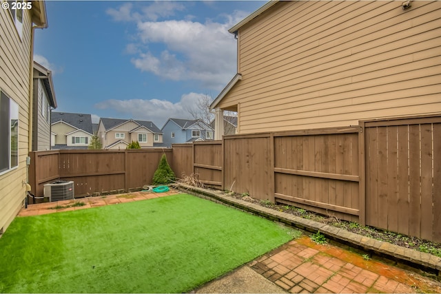 view of yard with central air condition unit, a fenced backyard, and a residential view