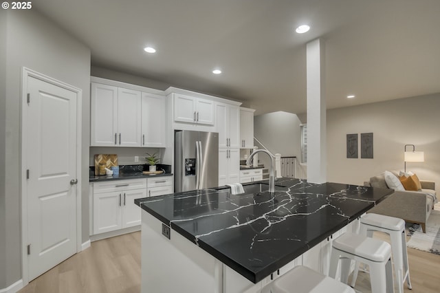 kitchen featuring dark countertops, a breakfast bar, white cabinetry, and stainless steel refrigerator with ice dispenser