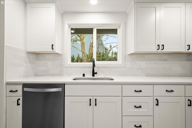 kitchen featuring light countertops, dishwasher, a sink, and white cabinetry