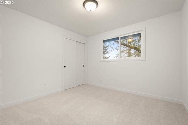 unfurnished room with light colored carpet and baseboards