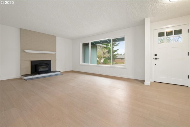 unfurnished living room featuring light wood-style floors, a textured ceiling, and baseboards