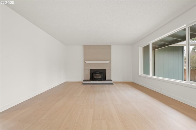 unfurnished living room with light wood-style floors, baseboards, and a textured ceiling